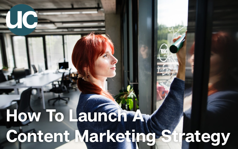 How To Launch A Content Marketing Strategy Featured Image: A woman with bright red hair writes on a window with an erasable marker.
