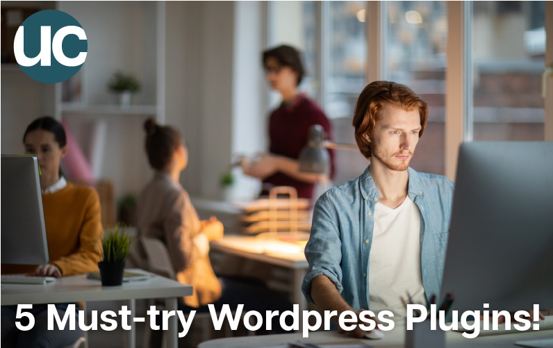 5 Must-try Wordpress Plugins! Featured Image: A man with red hair sits in a dark corner of the office on his computer looking at different wordpress plugins