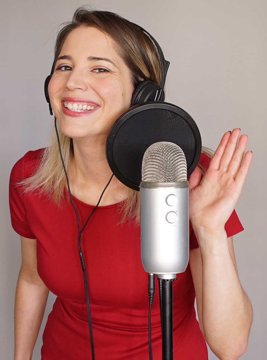 Emily Milling in red dress smiling beside a blue yeti microphone