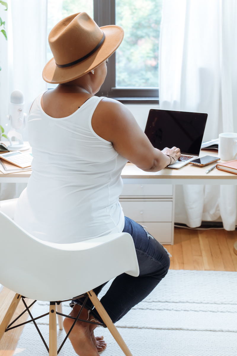 Woman in white tank top sitting at computer